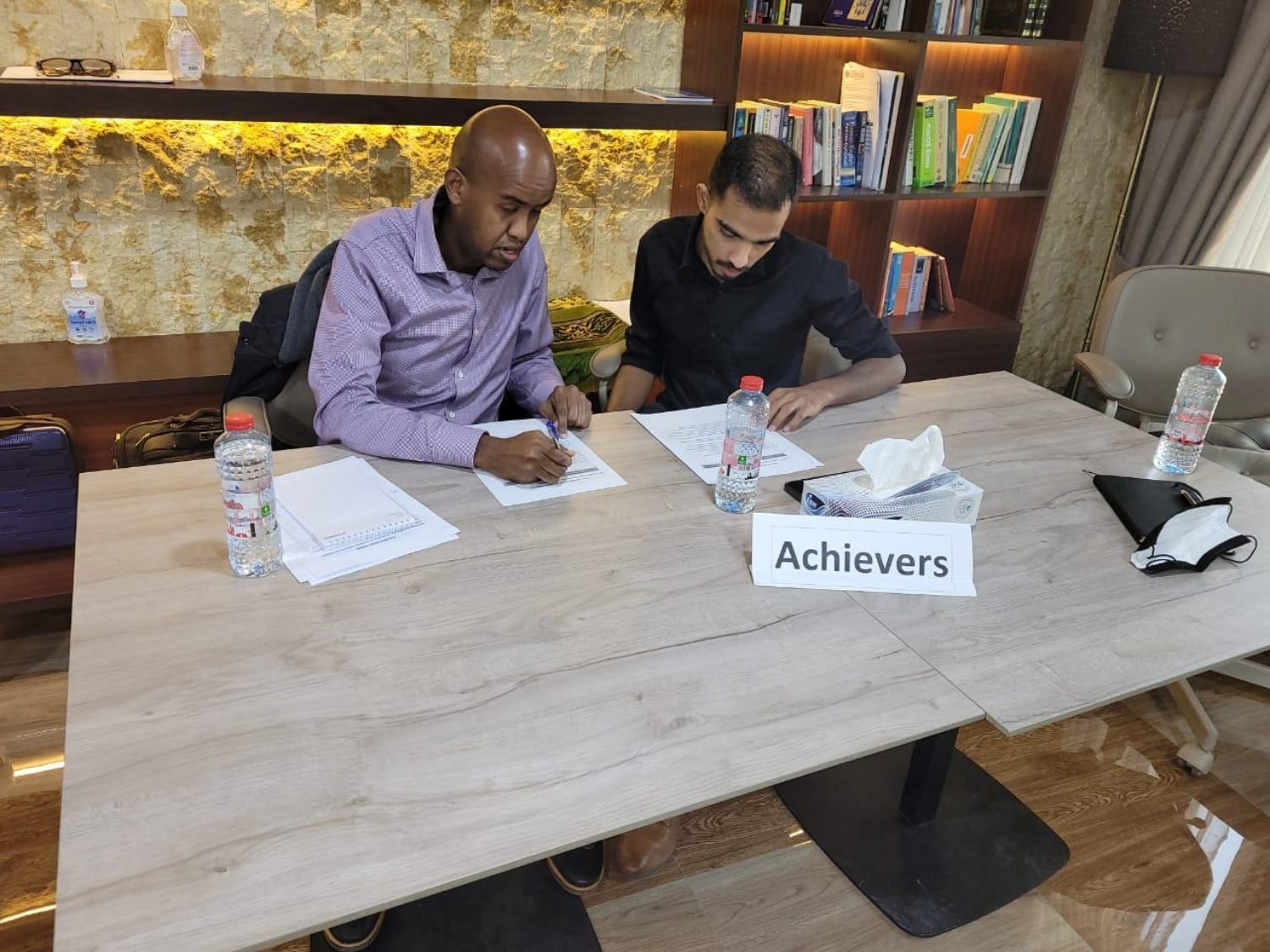 Two colleagues at a table marked Achievers, working through the worksheet
