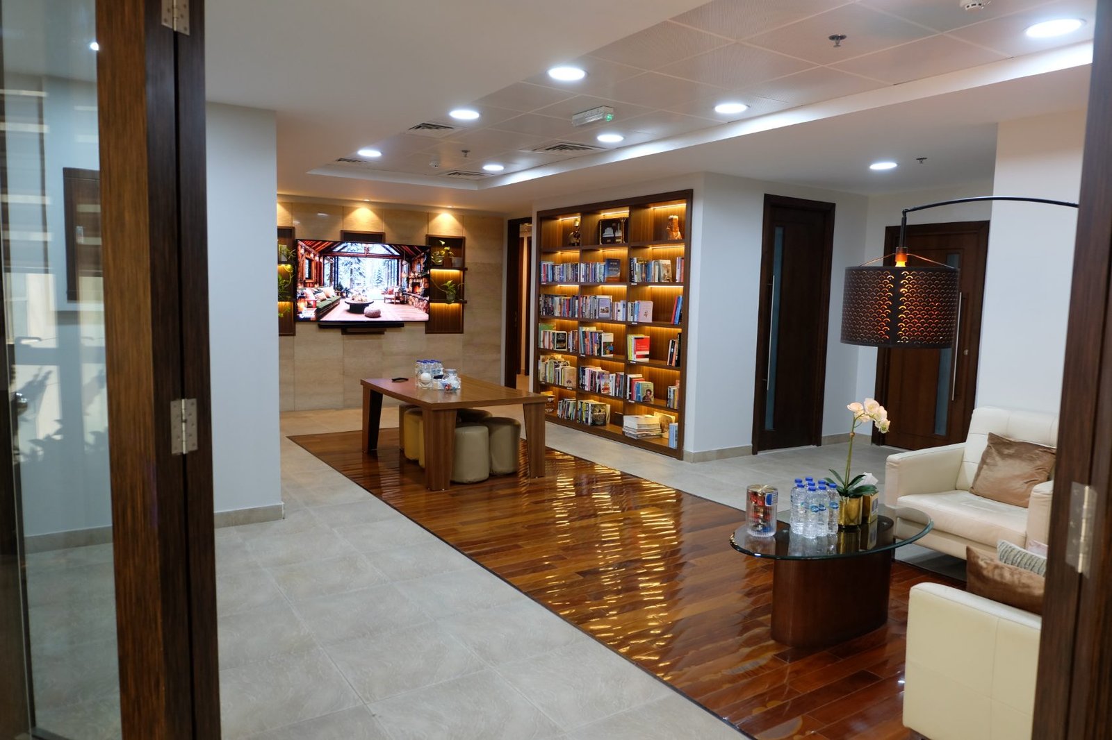 The Aquaness library — lit shelves running down both walls of the corridor, with a reading table between them